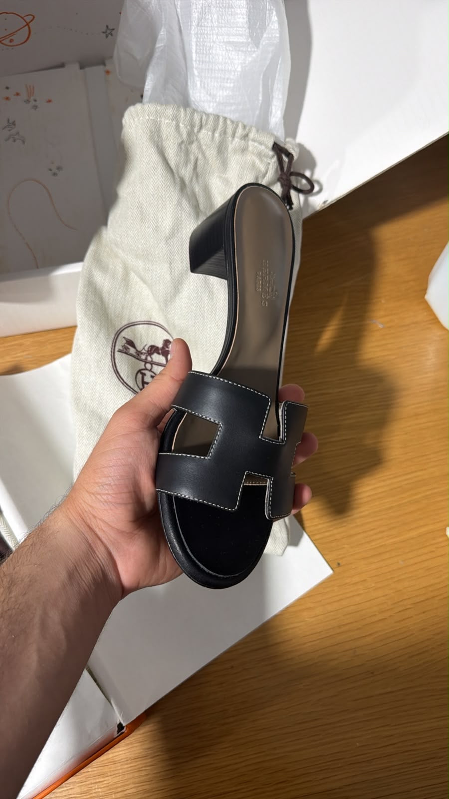 black Hermès Oasis sandals featuring the signature 'H' cut-out strap and a comfortable block heel.