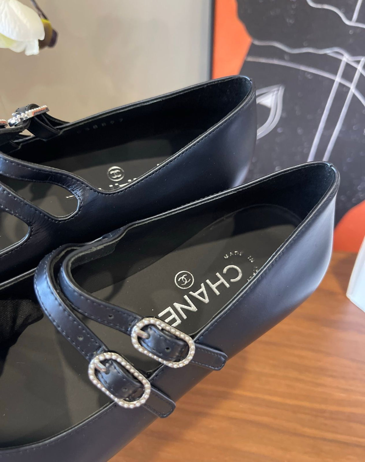 black Chanel Mary Jane flats featuring smooth leather bodies, double buckled straps, and grosgrain cap toes accented with an embroidered CC logo