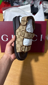 Gucci GG Supreme canvas flat sandals featuring the signature gold-toned Interlocking G hardware and adjustable velcro straps.