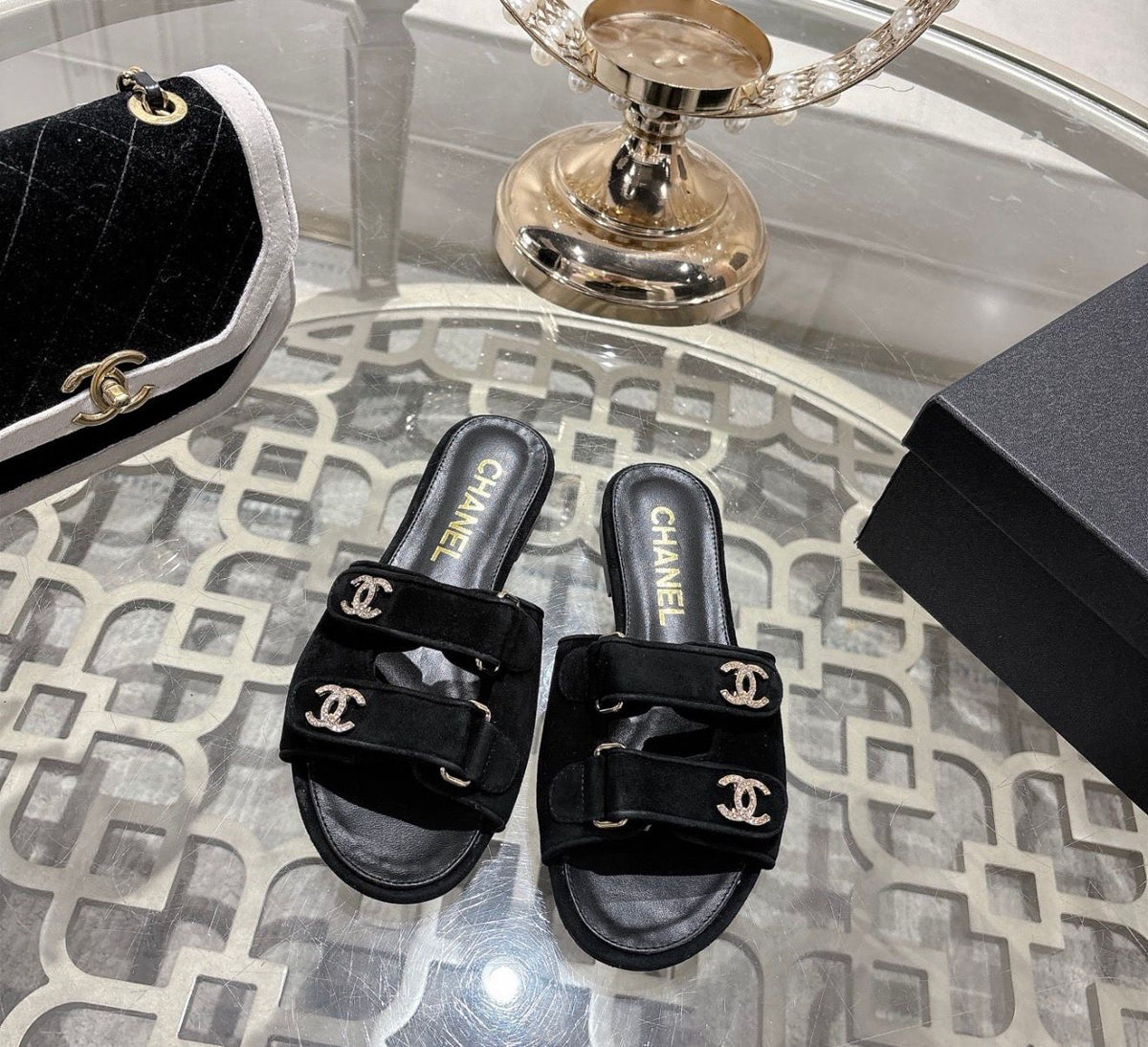 black suede Chanel flat mules featuring double Velcro straps with gold-tone hardware and crystal CC embellishments