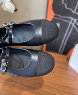 black Chanel Mary Jane flats featuring smooth leather bodies, double buckled straps, and grosgrain cap toes accented with an embroidered CC logo