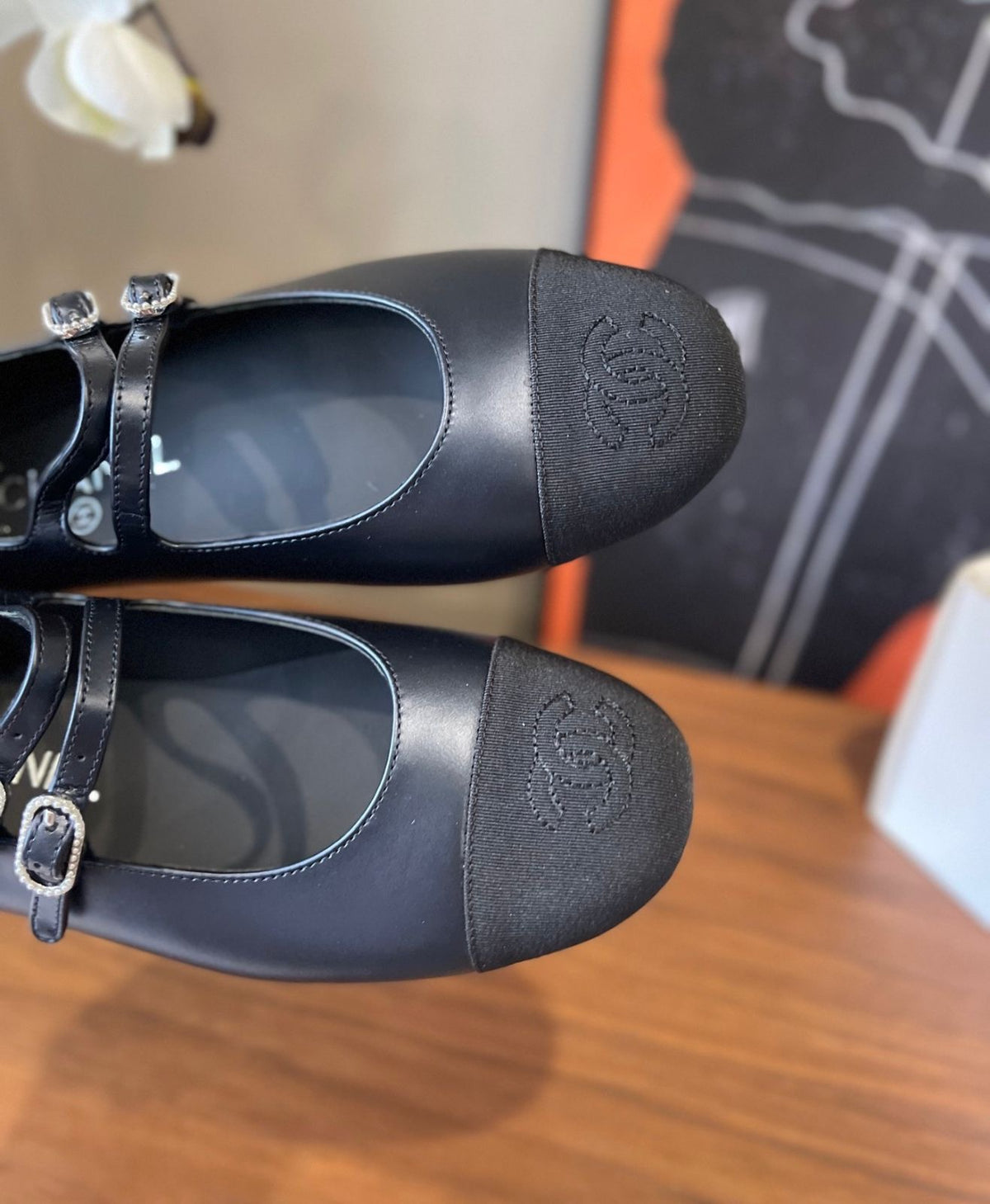 black Chanel Mary Jane flats featuring smooth leather bodies, double buckled straps, and grosgrain cap toes accented with an embroidered CC logo