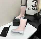 light pink and white Chanel Caoutchouk CC high rubber rain boots featuring the iconic interlocking CC logo on the shaft.