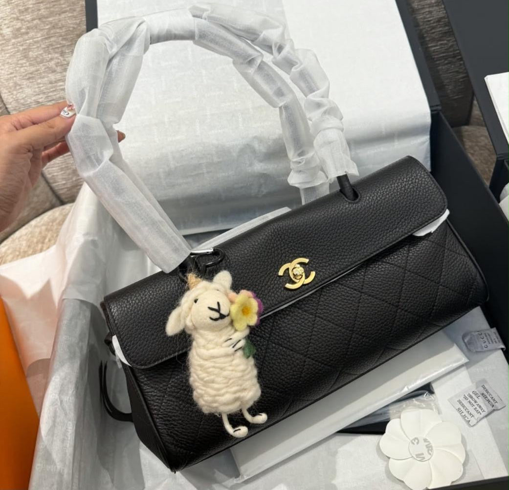 black quilted Chanel Small Shopping Bag in grained calfskin with gold-tone hardware, styled with a playful sheep bag charm.