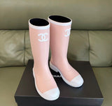 light pink and white Chanel Caoutchouk CC high rubber rain boots featuring the iconic interlocking CC logo on the shaft.