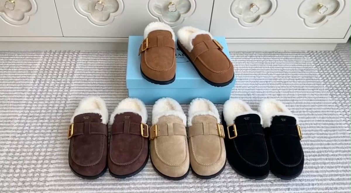 These cozy Prada suede shearling mules feature a soft, plush white shearling lining and an adjustable gold-tone side buckle
