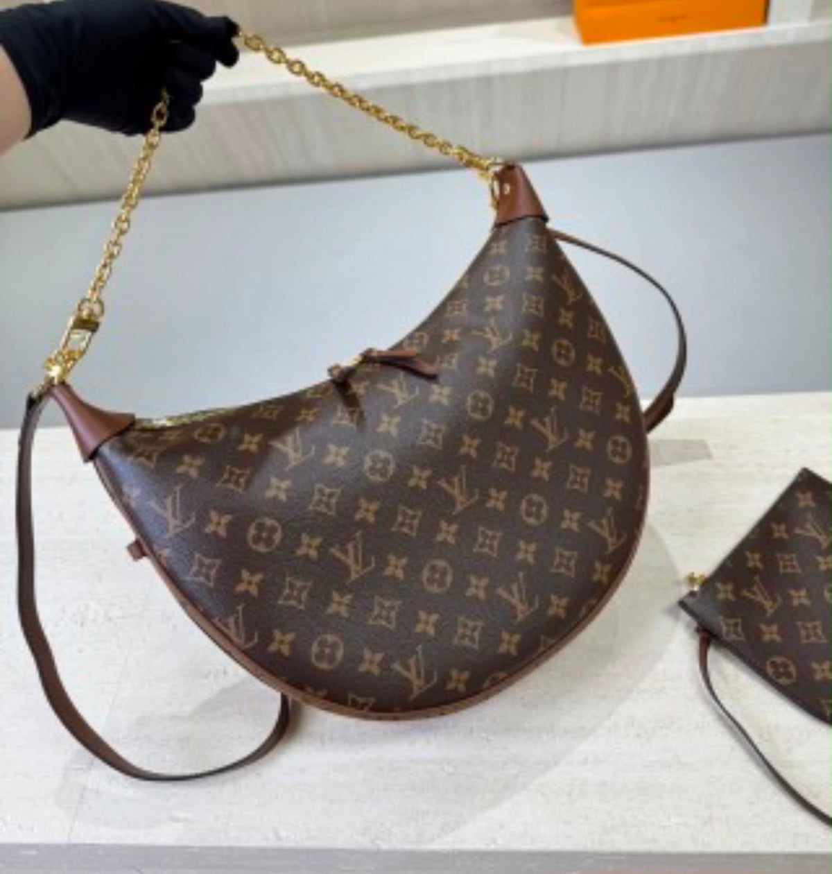 Louis Vuitton Loop Hobo in Monogram canvas with its distinctive half-moon silhouette accented by a gleaming gold-tone chain