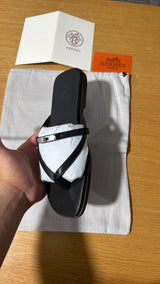 black calfskin Hermès Miss sandals featuring an interlaced thong silhouette and a mini version of the iconic palladium-plated Kelly buckle
