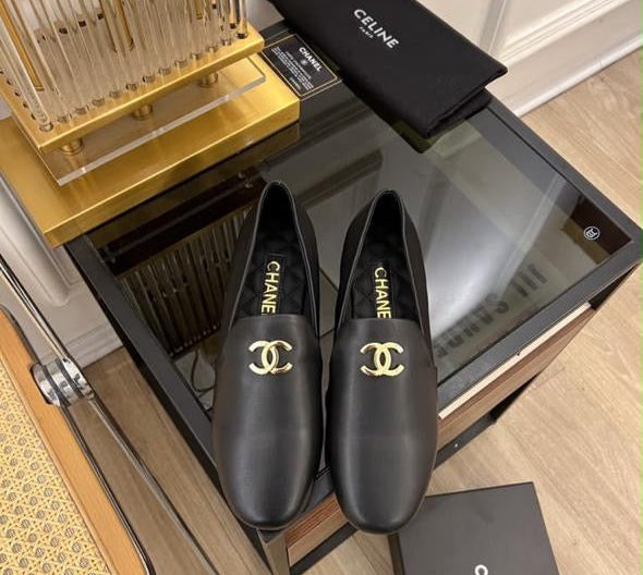 These are black leather Chanel CC logo loafers featuring polished gold-tone interlocking CC hardware on the vamp