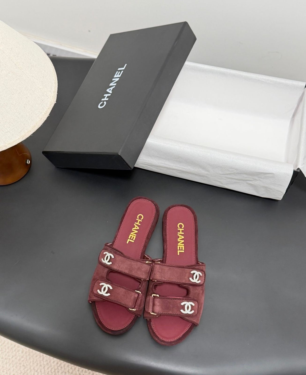 black suede Chanel flat mules featuring double Velcro straps with gold-tone hardware and crystal CC embellishments