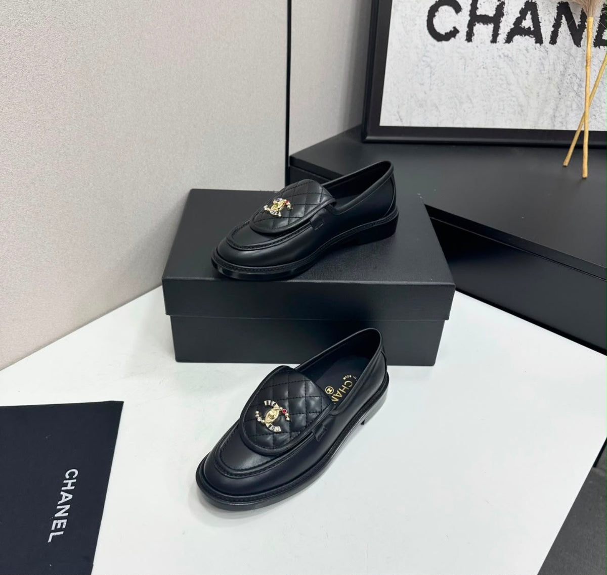 black lambskin Chanel Emblematics Moccasins featuring quilted detailing and an ornate jeweled CC logo embellishment