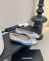 quilted leather ballet flats by Chanel, featuring the iconic interlocking CC logo and a delicate bow on the toe