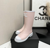 light pink and white Chanel Caoutchouk CC high rubber rain boots featuring the iconic interlocking CC logo on the shaft.