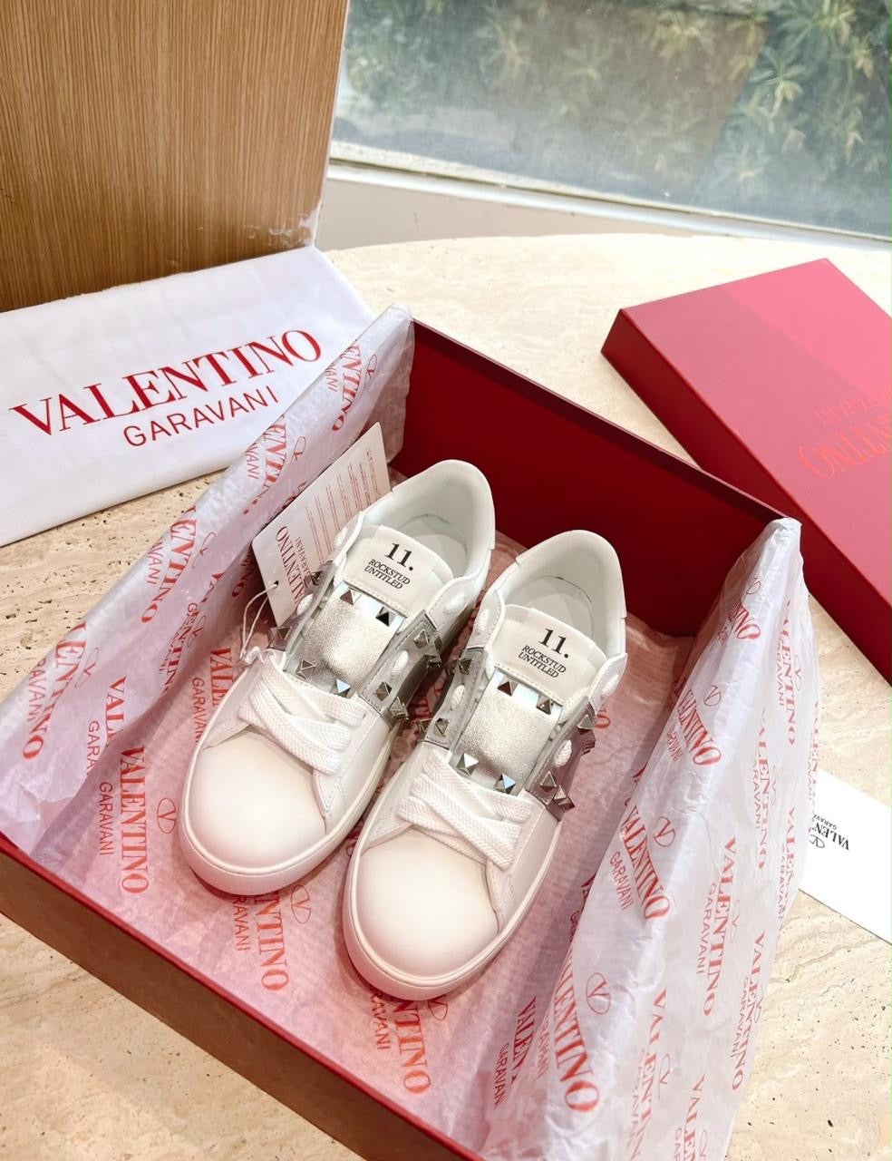 These are the Valentino Garavani Rockstud Untitled white leather low-top sneakers featuring signature pyramidal rockstud embellishments across the center band