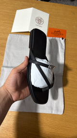 black calfskin Hermès Miss sandals featuring an interlaced thong silhouette and a mini version of the iconic palladium-plated Kelly buckle