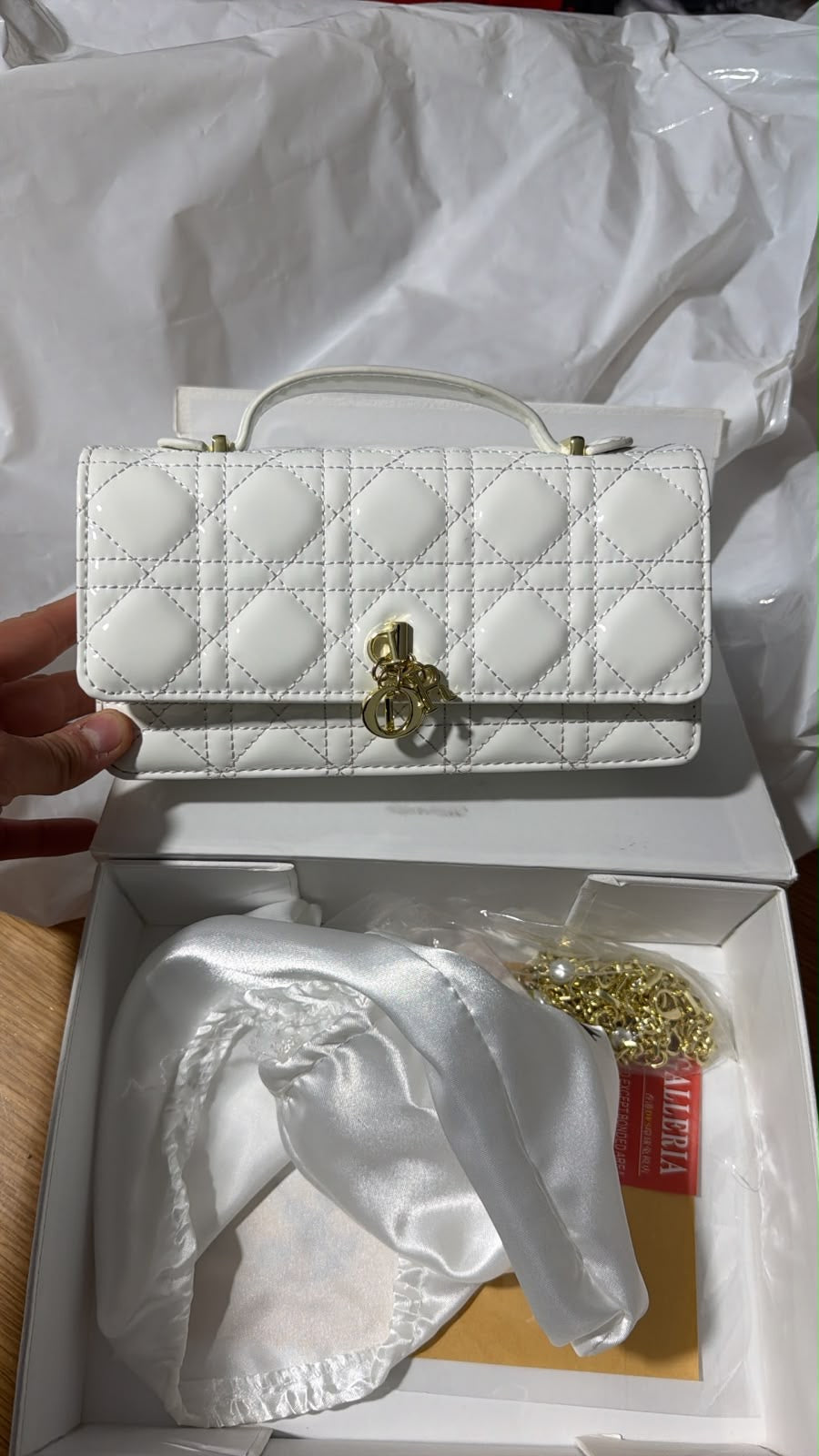 white shiny Cannage leather Dior My Dior Top Handle Bag complete with signature gold-tone D.I.O.R. charms on the front.