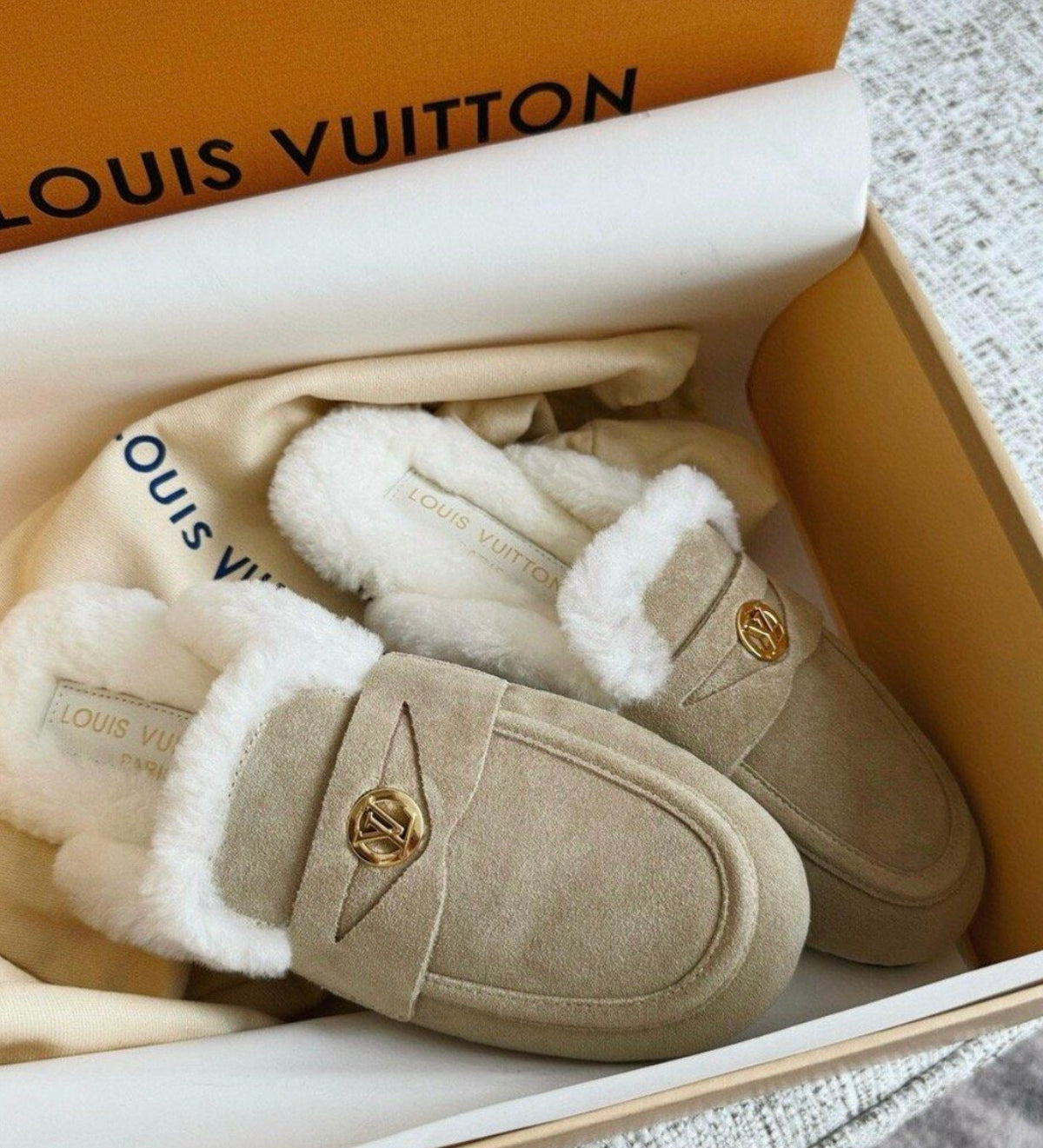 Louis Vuitton Soho Open Back Loafers crafted in soft suede calf leather with a plush shearling lining and a gold-toned LV Circle accessory