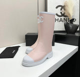 light pink and white Chanel Caoutchouk CC high rubber rain boots featuring the iconic interlocking CC logo on the shaft.