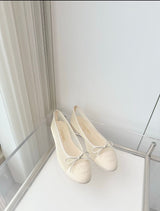 quilted leather ballet flats by Chanel, featuring the iconic interlocking CC logo and a delicate bow on the toe