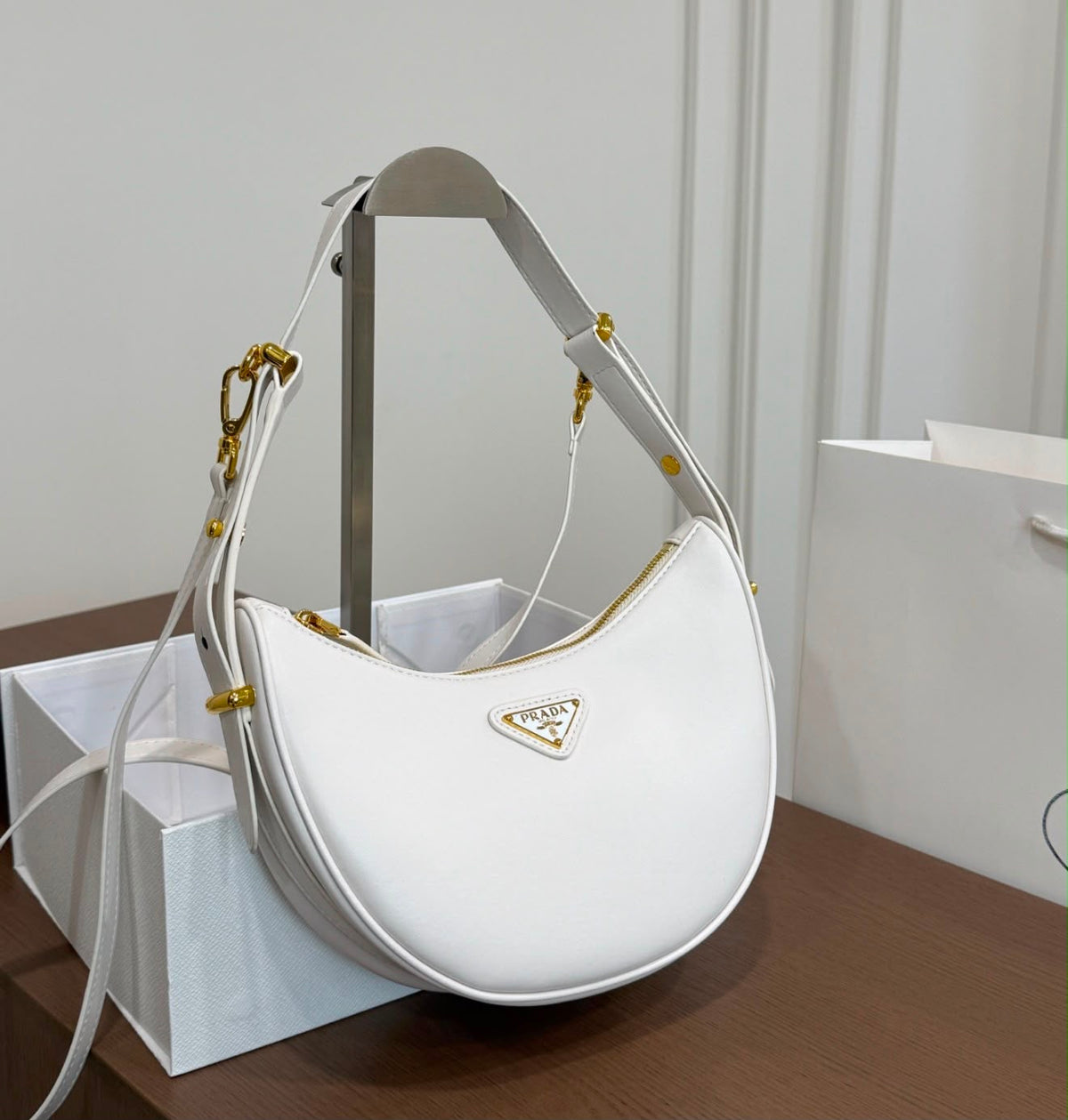 Prada Arqué Leather Shoulder Bag in white calfskin featuring polished gold-tone hardware and the brand's iconic enameled metal triangle logo