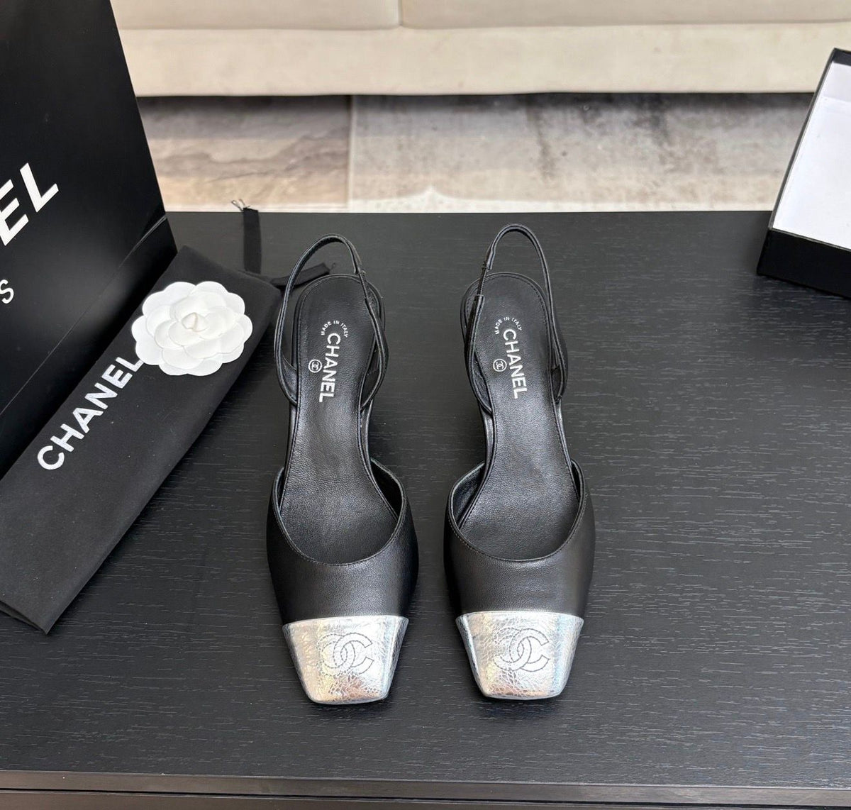 black leather slingback shoes with metallic silver cap toes featuring the signature Chanel CC logo