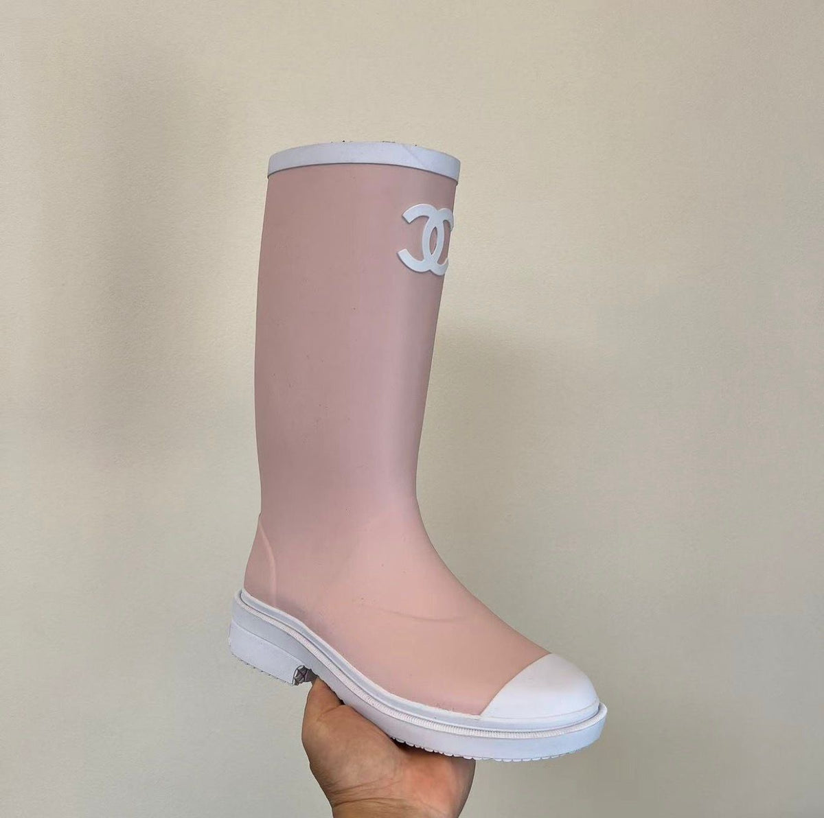 light pink and white Chanel Caoutchouk CC high rubber rain boots featuring the iconic interlocking CC logo on the shaft.