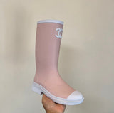 light pink and white Chanel Caoutchouk CC high rubber rain boots featuring the iconic interlocking CC logo on the shaft.