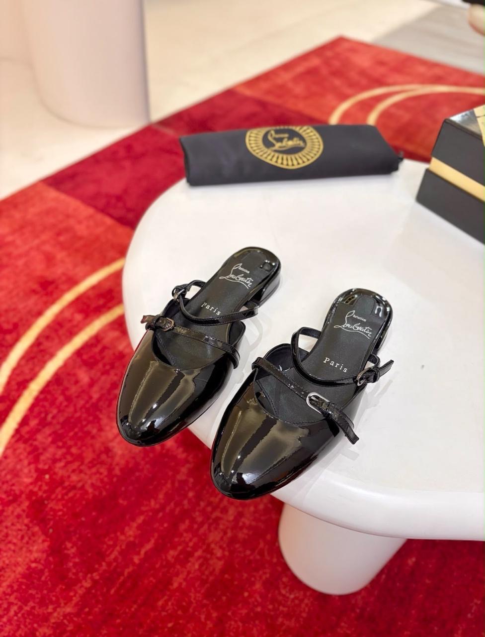 Christian Louboutin Jane Nina patent leather flat mules, featuring a sleek, glossy black finish and double buckled straps