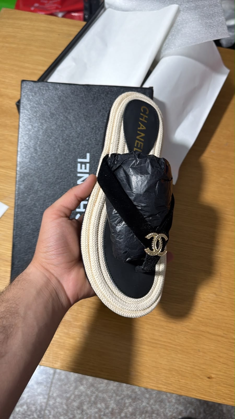 Chanel black thong slipper featuring a signature gold CC logo and a braided jute trim.