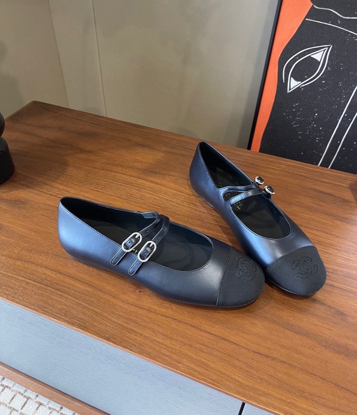 black Chanel Mary Jane flats featuring smooth leather bodies, double buckled straps, and grosgrain cap toes accented with an embroidered CC logo
