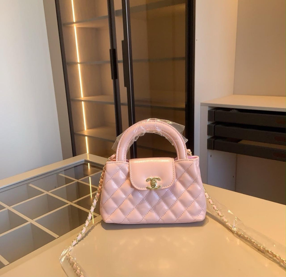 light pink Chanel quilted shiny aged calfskin nano Kelly mini shopper features a classic CC turn-lock closure and interwoven chain strap