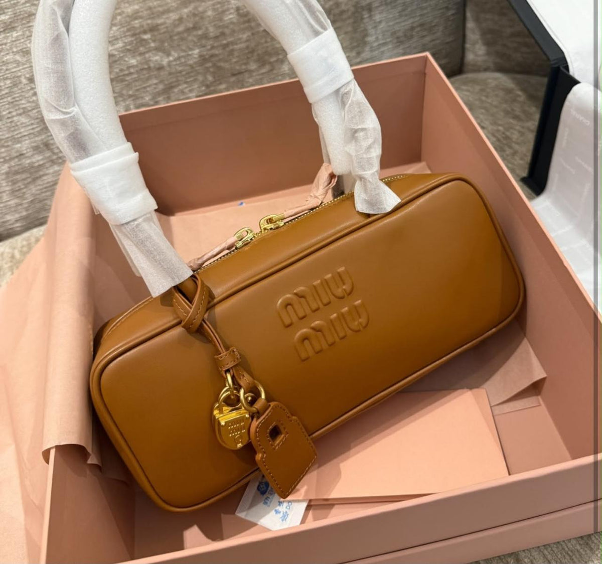 brown Miu Miu Small Beau Leather Bag featuring an embossed logo on the front and gold-tone hardware
